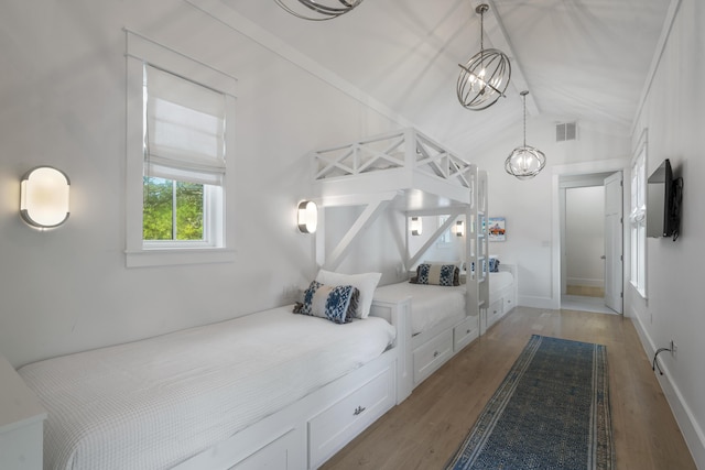 bedroom with lofted ceiling, a chandelier, visible vents, and light wood-style floors