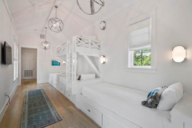 bedroom featuring a notable chandelier, light hardwood / wood-style floors, and lofted ceiling