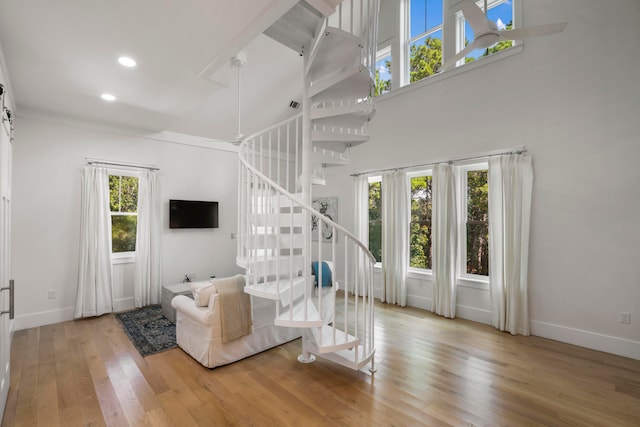 unfurnished living room featuring light hardwood / wood-style floors, a healthy amount of sunlight, and a high ceiling