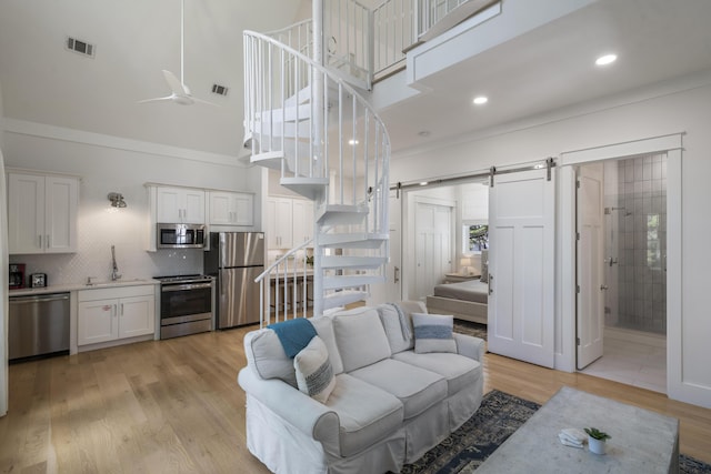 living area featuring a barn door, a high ceiling, stairs, and visible vents