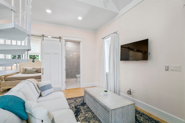 living room with crown molding, hardwood / wood-style flooring, and a barn door