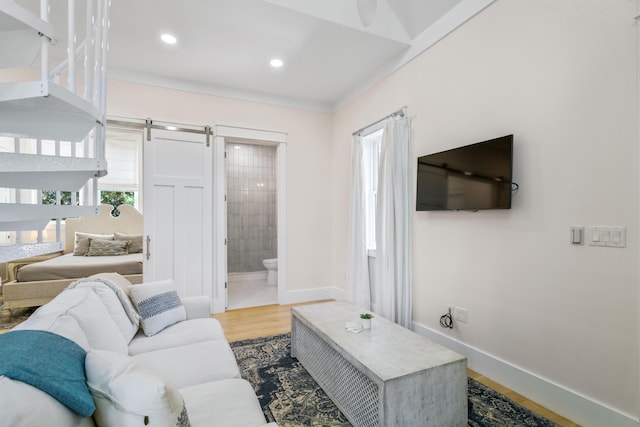 living area featuring wood finished floors, baseboards, recessed lighting, and a barn door