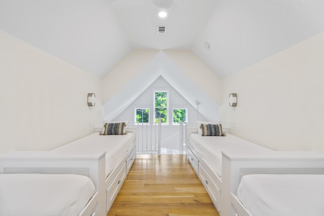 bedroom featuring light wood-type flooring, visible vents, and lofted ceiling