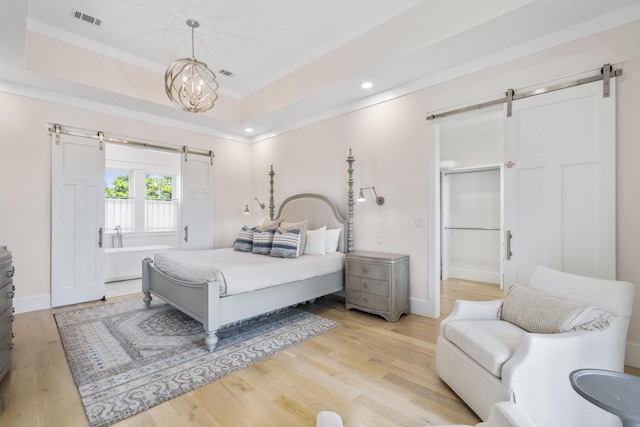 bedroom featuring a barn door, light wood-style floors, visible vents, and recessed lighting