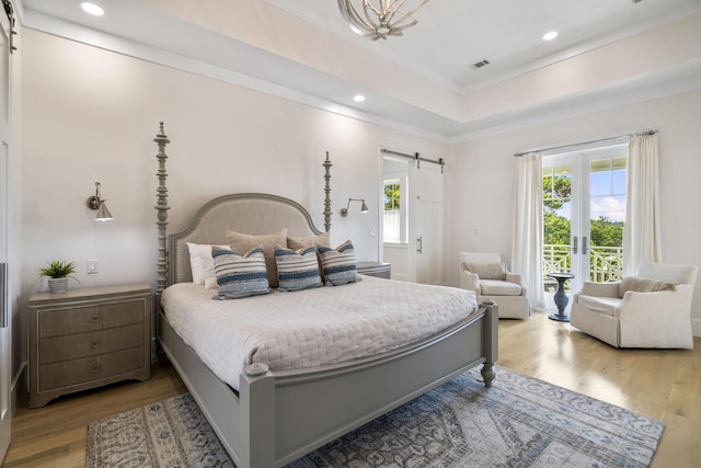 bedroom with a barn door, recessed lighting, light wood-type flooring, crown molding, and access to outside