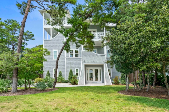 rear view of house featuring a balcony, a lawn, and french doors