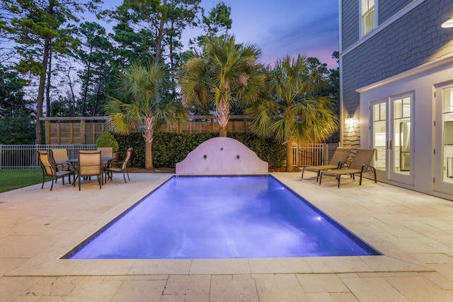 pool at dusk with a fenced backyard, a patio, and a fenced in pool