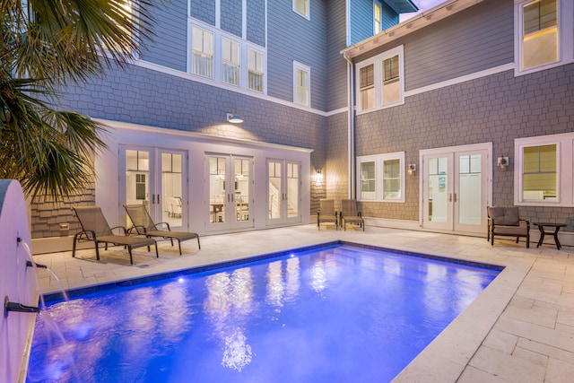 view of swimming pool with a patio area, french doors, and pool water feature