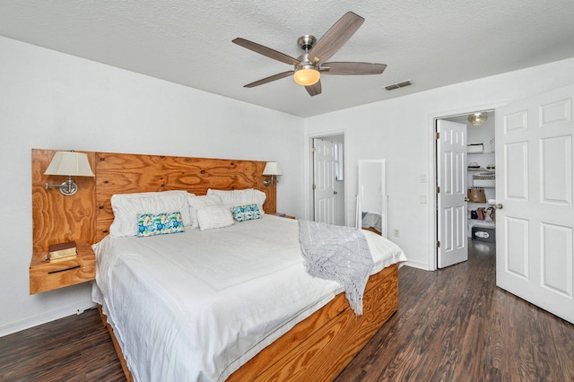 bedroom with ceiling fan, dark wood-type flooring, and a textured ceiling