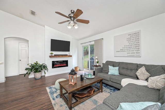 living room with hardwood / wood-style floors, a large fireplace, a textured ceiling, lofted ceiling, and ceiling fan