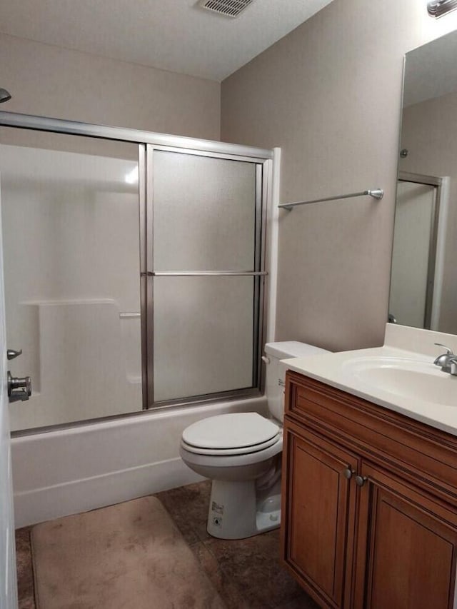 full bath with combined bath / shower with glass door, vanity, toilet, and tile patterned floors