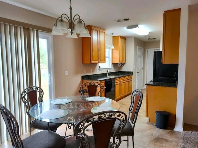 kitchen with black appliances, a chandelier, a sink, brown cabinets, and dark stone counters