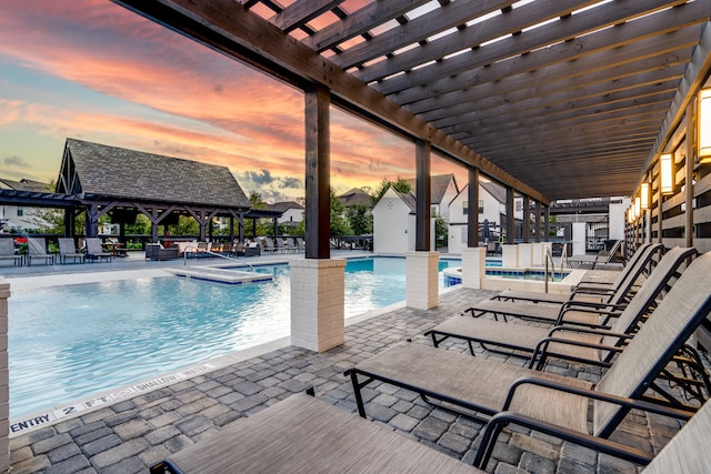 pool at dusk with a gazebo, a hot tub, and a patio area