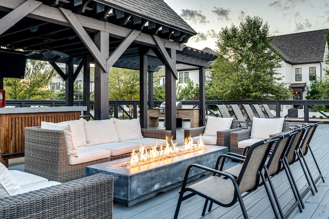 deck at dusk featuring an outdoor living space with a fire pit