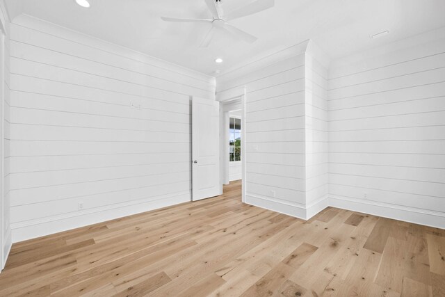 spare room featuring ceiling fan, wooden walls, and light hardwood / wood-style flooring