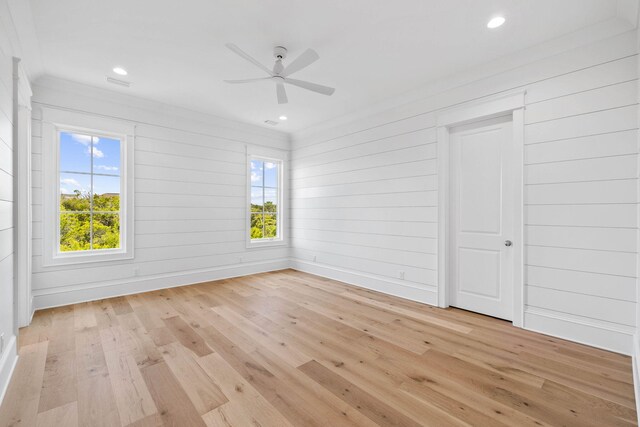 unfurnished room with crown molding, ceiling fan, wood walls, and light hardwood / wood-style floors