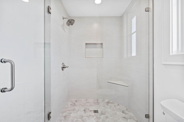 bathroom with toilet and a shower with shower door