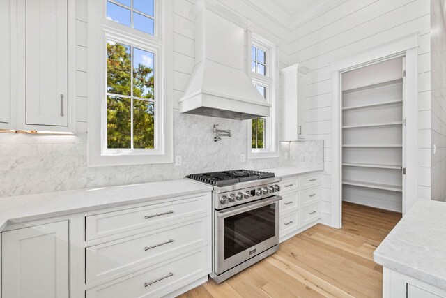 kitchen featuring light wood-type flooring, white cabinetry, light stone counters, and stainless steel stove