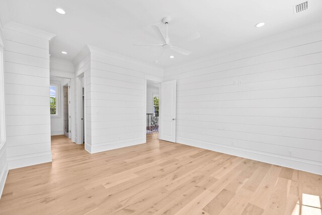 spare room featuring ceiling fan, wooden walls, light hardwood / wood-style floors, and ornamental molding