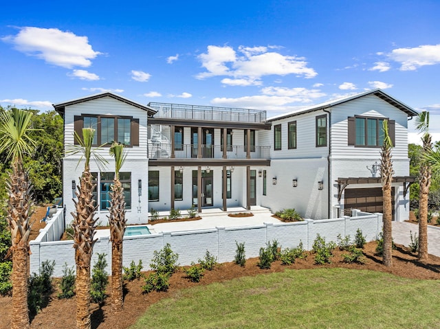 back of house with a balcony, a garage, and a fenced in pool