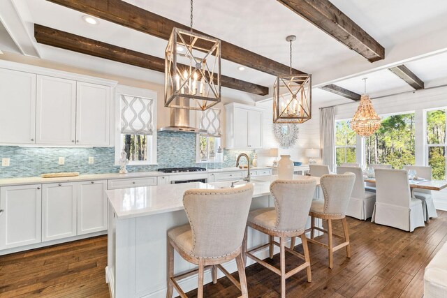 kitchen featuring dark hardwood / wood-style floors, pendant lighting, white cabinets, beam ceiling, and gas cooktop