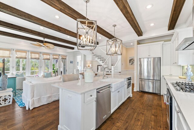 kitchen featuring dark hardwood / wood-style floors, stainless steel appliances, pendant lighting, and a center island with sink