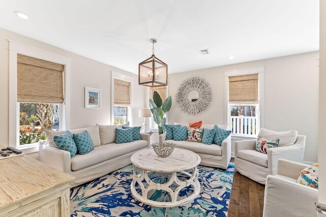 living room with a notable chandelier, a healthy amount of sunlight, and dark wood-type flooring