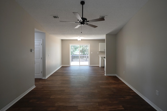 unfurnished room with ceiling fan, dark wood-type flooring, and a textured ceiling