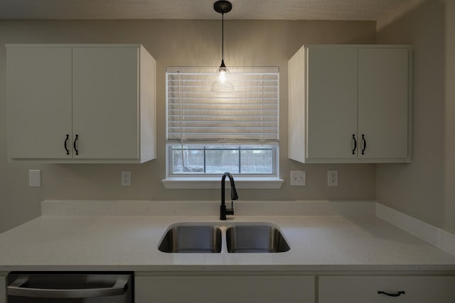 kitchen featuring dishwasher, sink, light stone countertops, and white cabinets