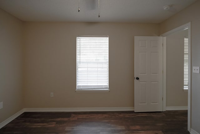 spare room with a wealth of natural light, a textured ceiling, and dark hardwood / wood-style floors