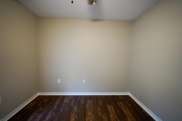 spare room with a textured ceiling and dark hardwood / wood-style floors