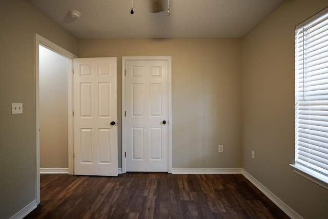 unfurnished bedroom with dark hardwood / wood-style floors, a textured ceiling, and multiple windows