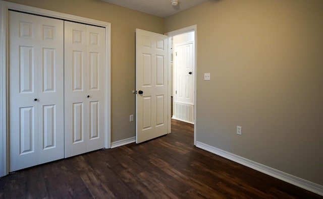 unfurnished bedroom with a closet and dark hardwood / wood-style flooring