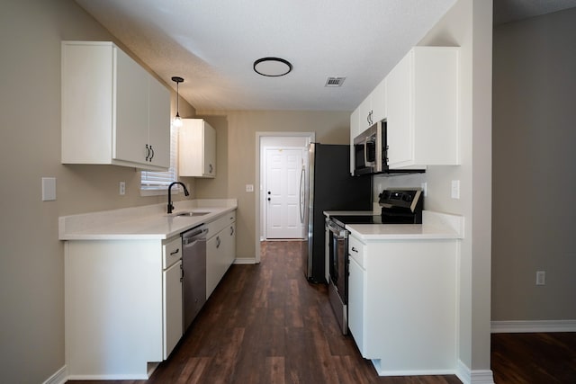 kitchen with stainless steel appliances, white cabinetry, dark hardwood / wood-style floors, sink, and hanging light fixtures