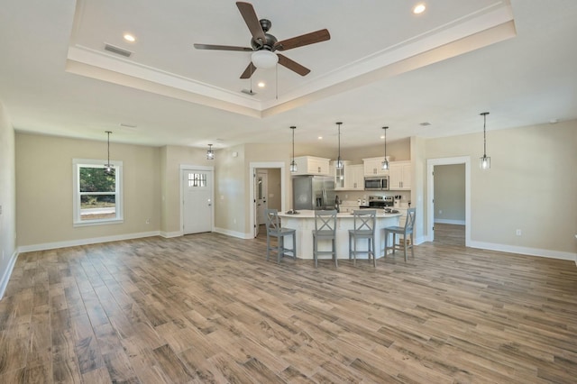 kitchen with stainless steel appliances, a raised ceiling, white cabinets, and hanging light fixtures