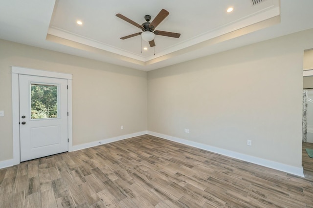 unfurnished room featuring light wood-type flooring, a tray ceiling, ceiling fan, and crown molding