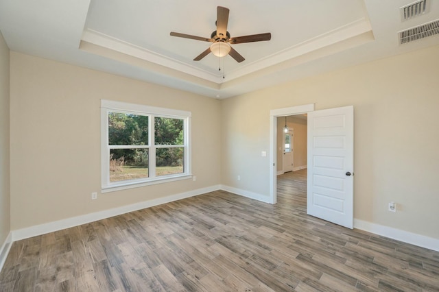 empty room featuring a tray ceiling and hardwood / wood-style flooring