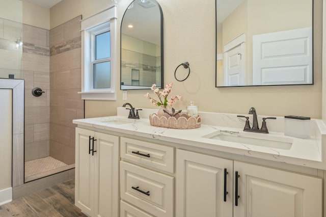 bathroom featuring hardwood / wood-style floors, vanity, and tiled shower