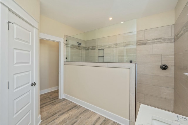 bathroom with tiled shower and hardwood / wood-style floors