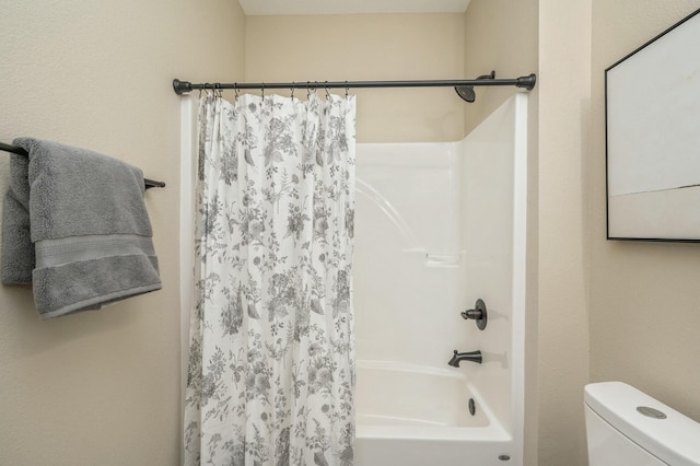 bathroom featuring shower / tub combo and toilet