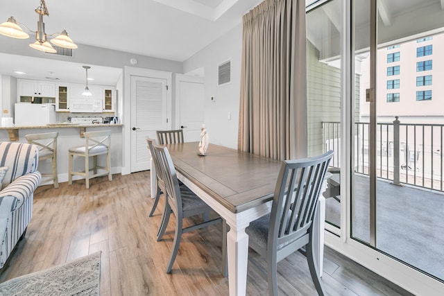 dining room with light wood-type flooring and a chandelier