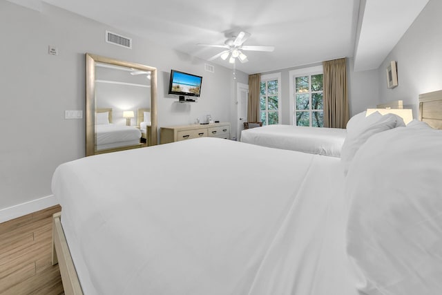 bedroom featuring a ceiling fan, wood finished floors, visible vents, and baseboards