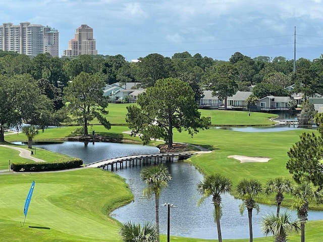 view of property's community with a water view, a lawn, and golf course view