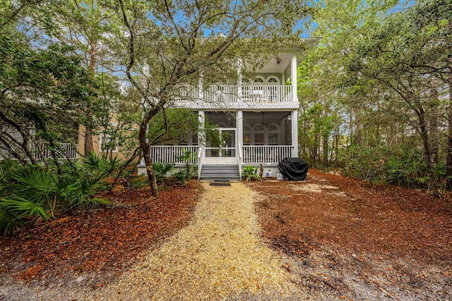 rear view of property with ceiling fan and a balcony