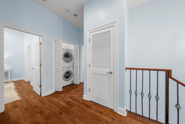 corridor with stacked washer and clothes dryer and dark hardwood / wood-style flooring