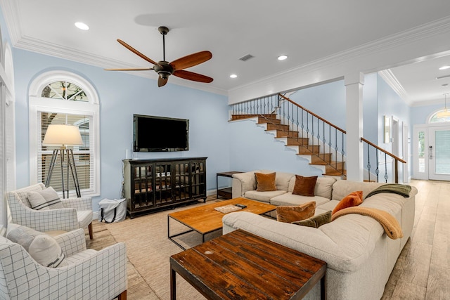 living room featuring light wood-type flooring, ornamental molding, a healthy amount of sunlight, and ceiling fan