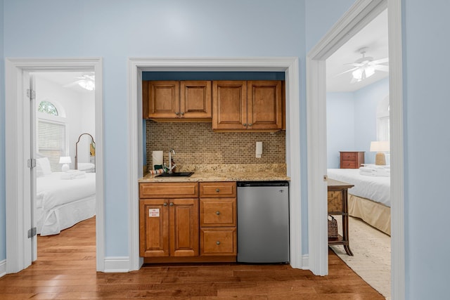 bar with hardwood / wood-style flooring, light stone counters, sink, stainless steel fridge, and ceiling fan