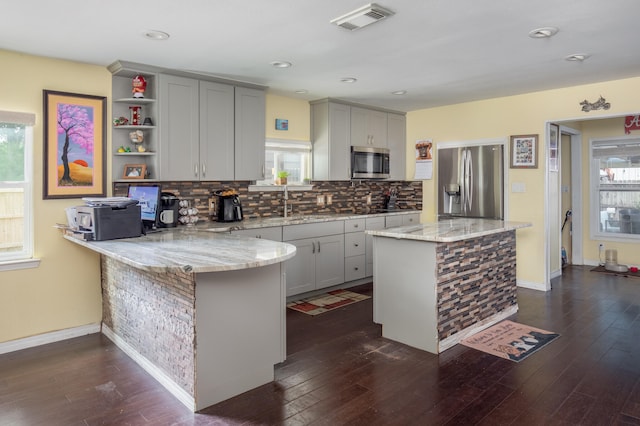 kitchen with backsplash, stainless steel appliances, a center island, and light stone countertops