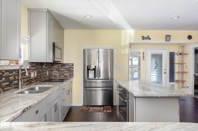 kitchen featuring backsplash, sink, light stone countertops, dark hardwood / wood-style floors, and stainless steel appliances