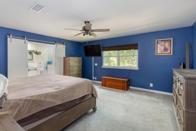 carpeted bedroom featuring ceiling fan, connected bathroom, and a barn door